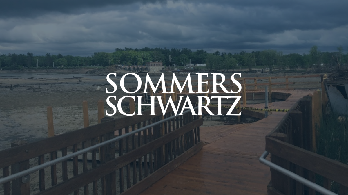 Sommers Schwartz logo overlaid on a wooden dock extending over a muddy shoreline under dark storm clouds