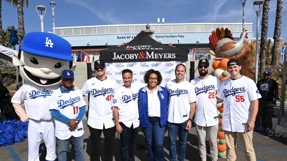 Jacoby & Meyers Teams Up With the Los Angeles Dodgers to Provide Thanksgiving Meals to 2,000 Families in Need 1 Group of people in LA Dodgers jerseys posing with mascot in front of Jacoby & Meyers tent at Dodger Stadium's Retired Numb...