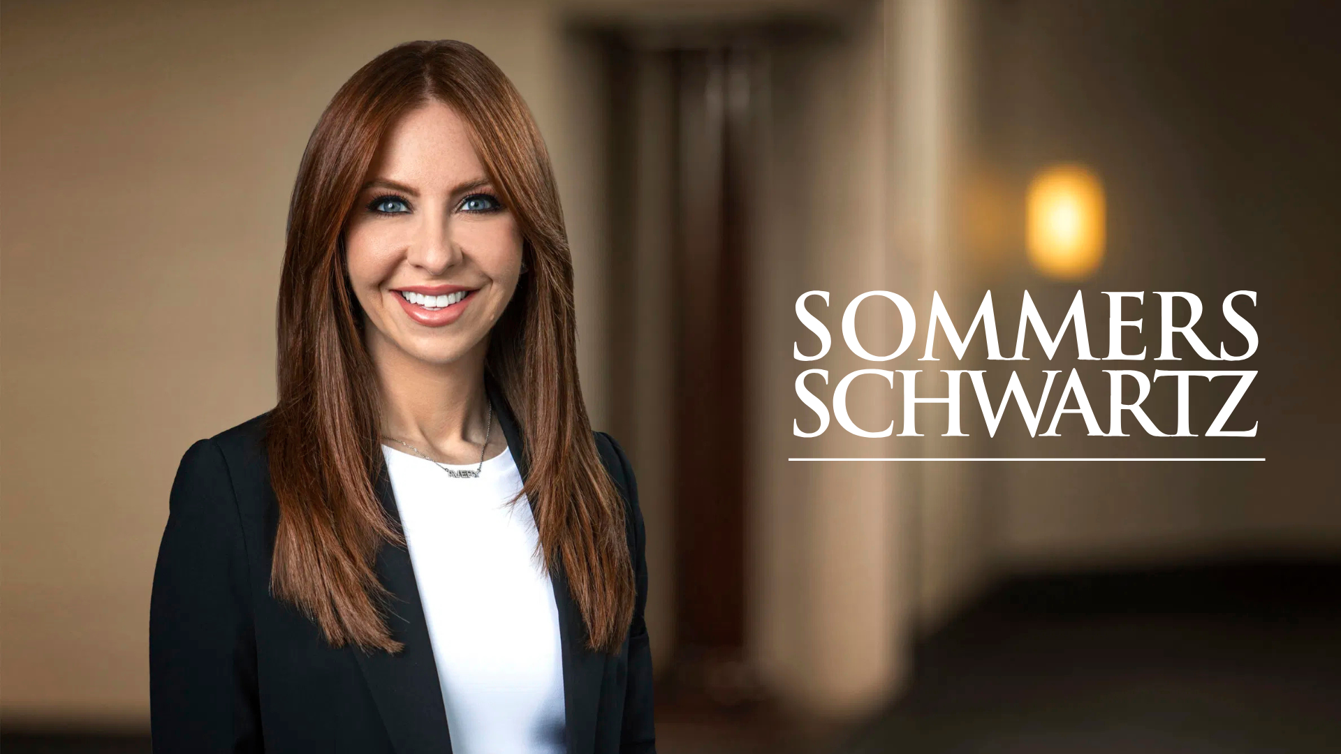 Professional headshot of a smiling woman with long auburn hair in a black blazer, beside the Sommers Schwartz law firm logo.
