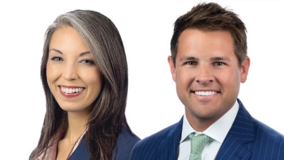 Woman with gray-streaked dark hair and man in navy pinstripe suit with green tie, both smiling against white background